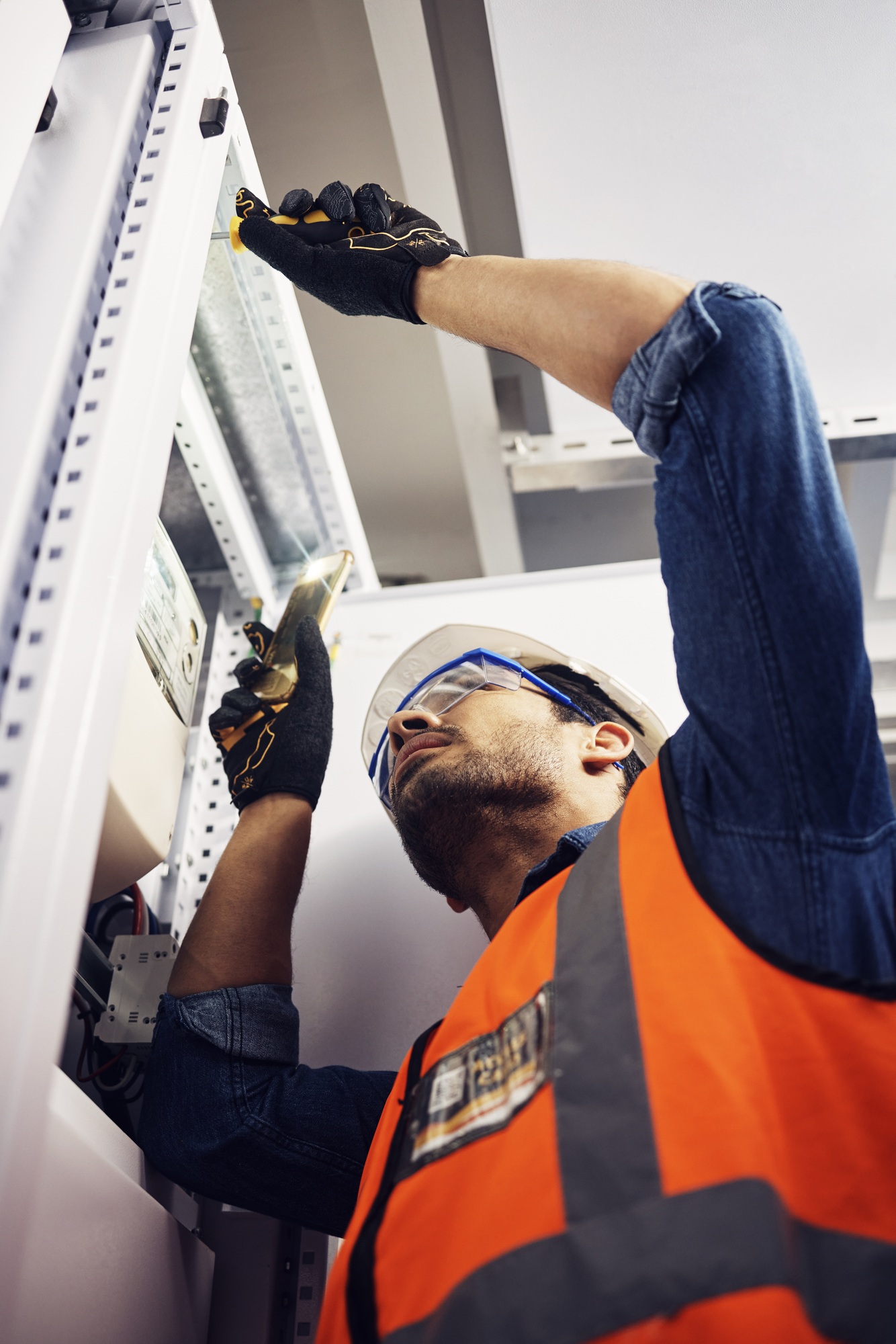 Ingeniero, electricista y encargado de mantenimiento con un destornillador en la sala de control de la caja de control. Técnico masculino